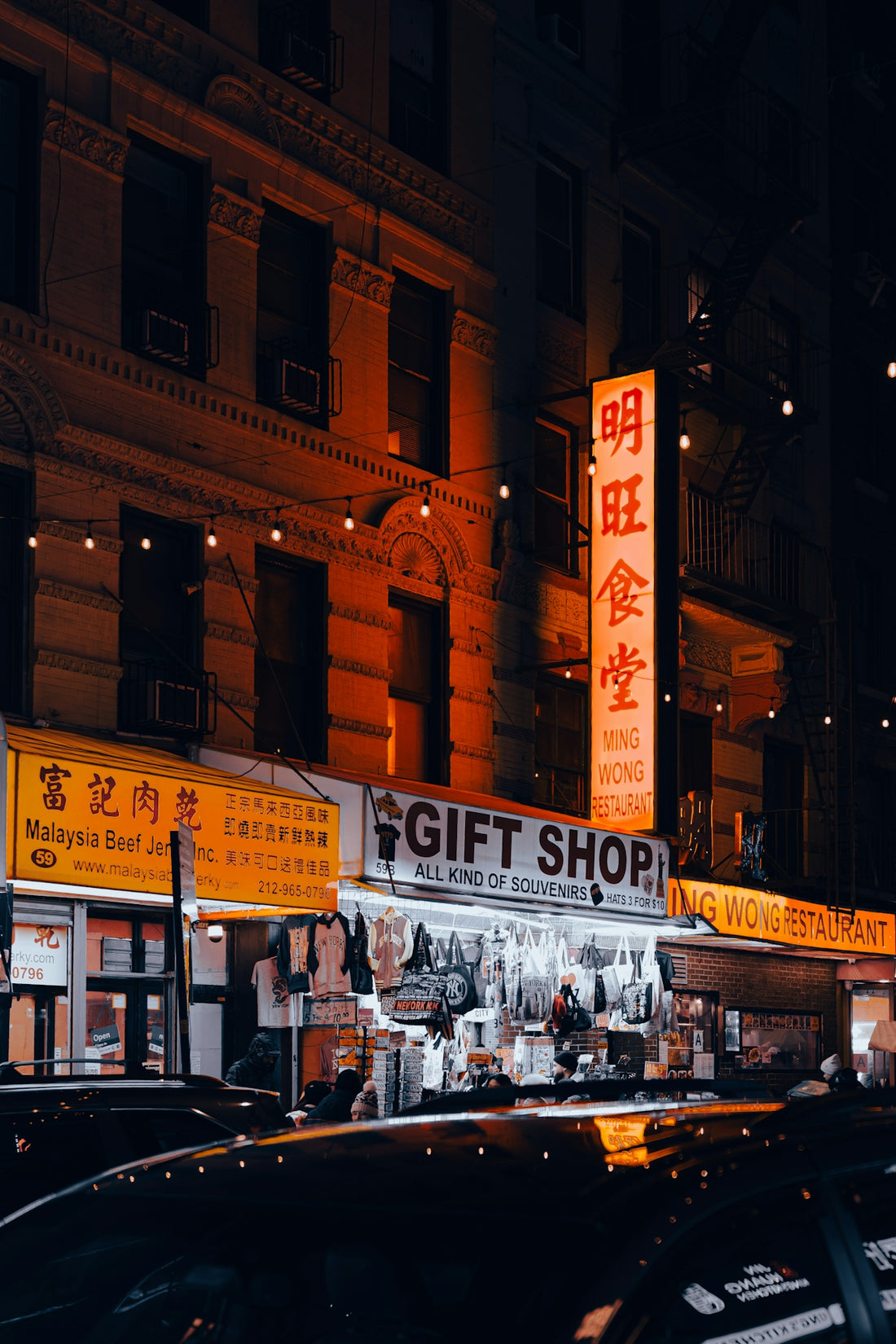 City street at night with illuminated shops and signs.